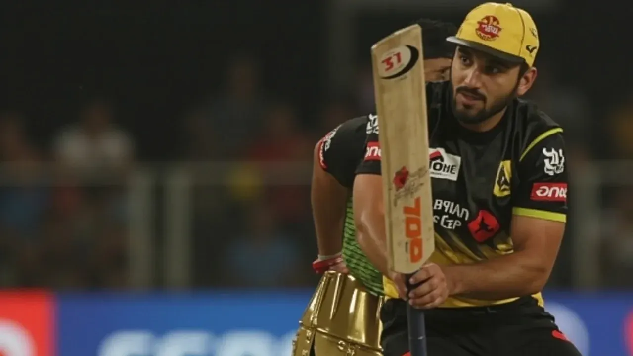 A batter playing an attacking cricket stroke during a night T20 match